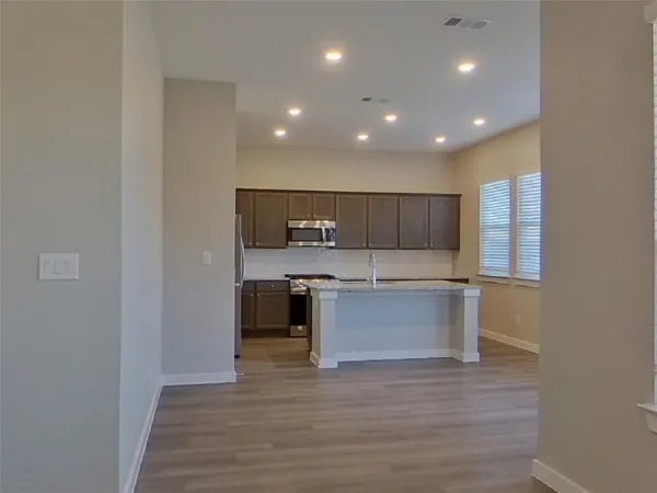 a large kitchen with a center island and wooden floor