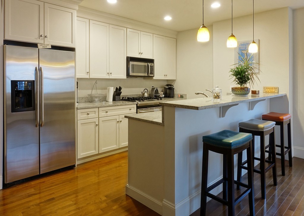 116 Rantoul Street, Unit 210 Beverly, MA 01915 - Photo 6 of 16 a kitchen with kitchen island granite countertop a table chairs sink and cabinets
