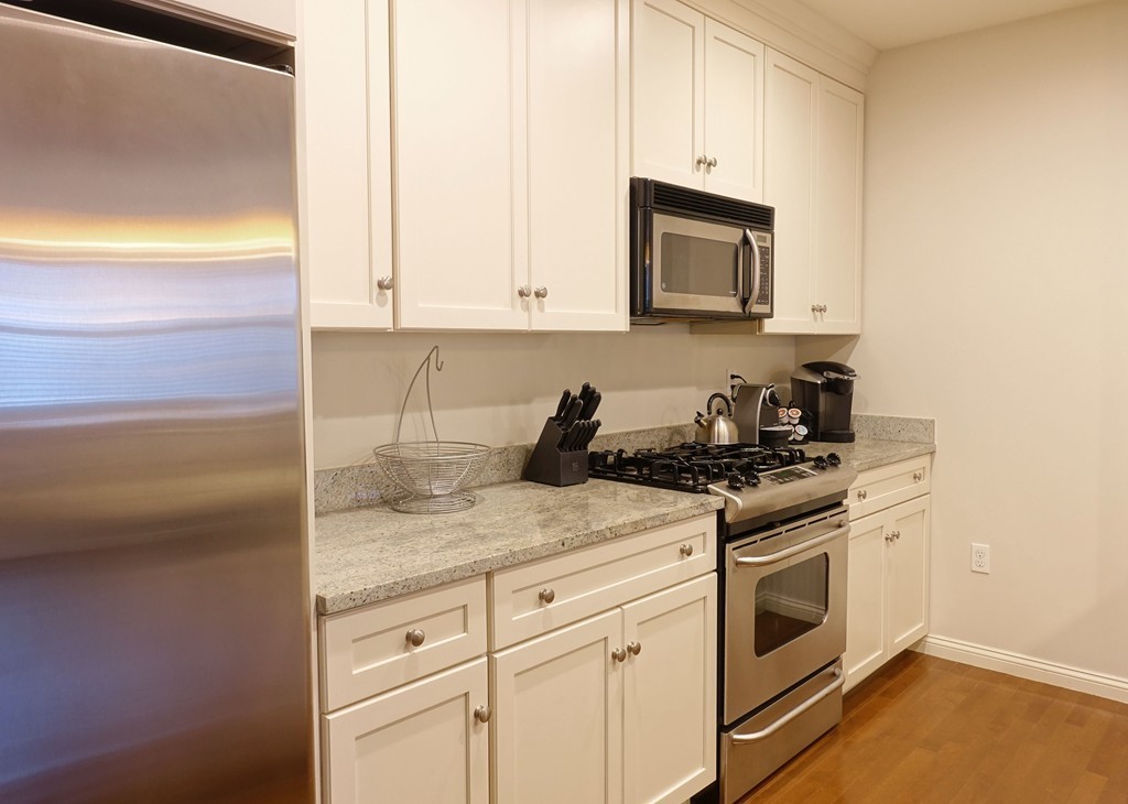 116 Rantoul Street, Unit 210 Beverly, MA 01915 - Photo 9 of 16 a kitchen with granite countertop white cabinets and white appliances
