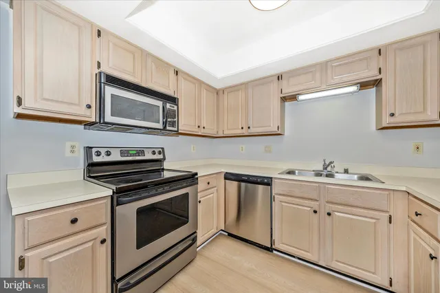 a kitchen with cabinets stainless steel appliances and sink