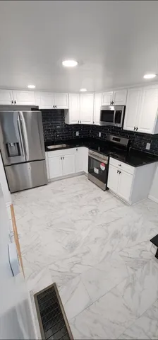 a large white kitchen with stainless steel appliances