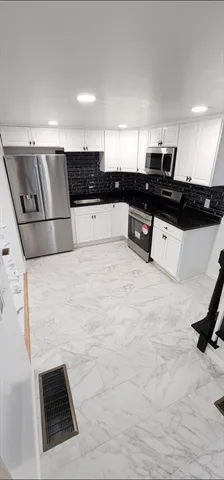 a kitchen with stainless steel appliances kitchen island granite countertop a stove and a sink