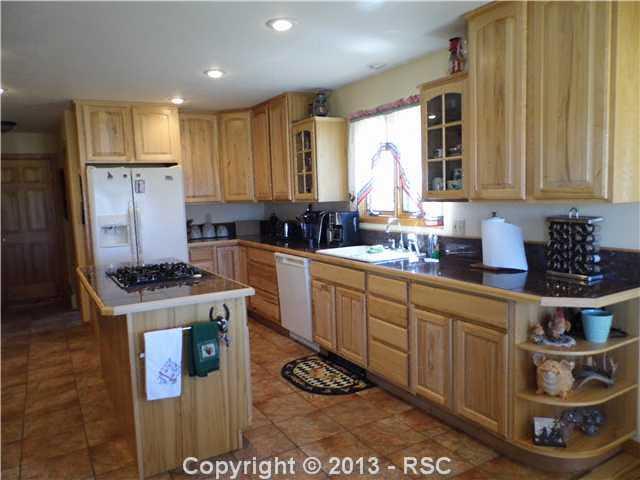 1450 Buck Road Calhan, CO 80808 - Photo 4 of 25 The kitchen has pantry, tons of cabinet storage, wall oven, built in microwave, gas stove top on the island, granite counters, tile floors & w/ a breakfast nook looking to Pikes Peak. One word....gorgeous.Don't forget refrigerator, washer & dryer included
