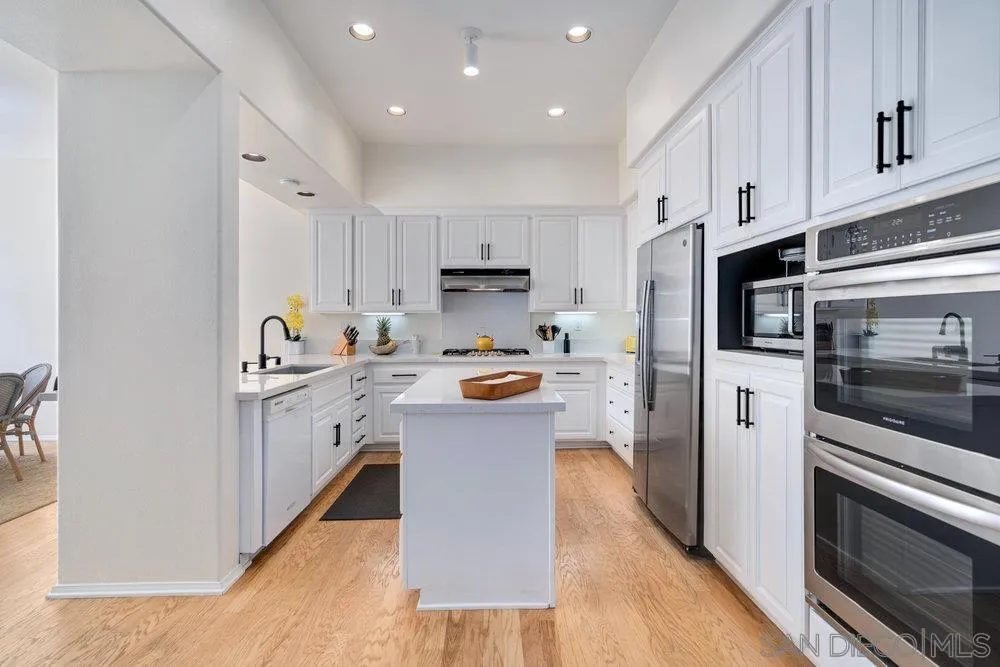 9636 Claiborne Square La Jolla, CA 92037 - Photo 20 of 48 a kitchen with white cabinets and stainless steel appliances