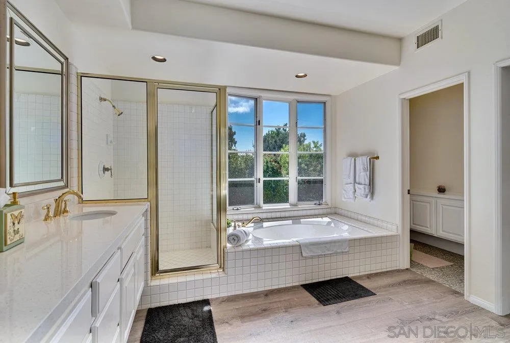 9636 Claiborne Square La Jolla, CA 92037 - Photo 28 of 48 a bathroom with a tub mirror and window