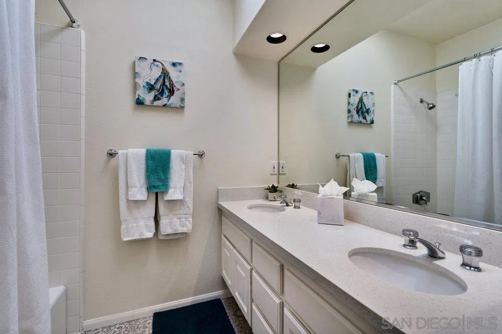 9636 Claiborne Square La Jolla, CA 92037 - Photo 33 of 48 a bathroom with a double vanity sink and a mirror