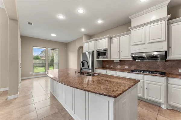 a kitchen with kitchen island granite countertop a stove sink and cabinets