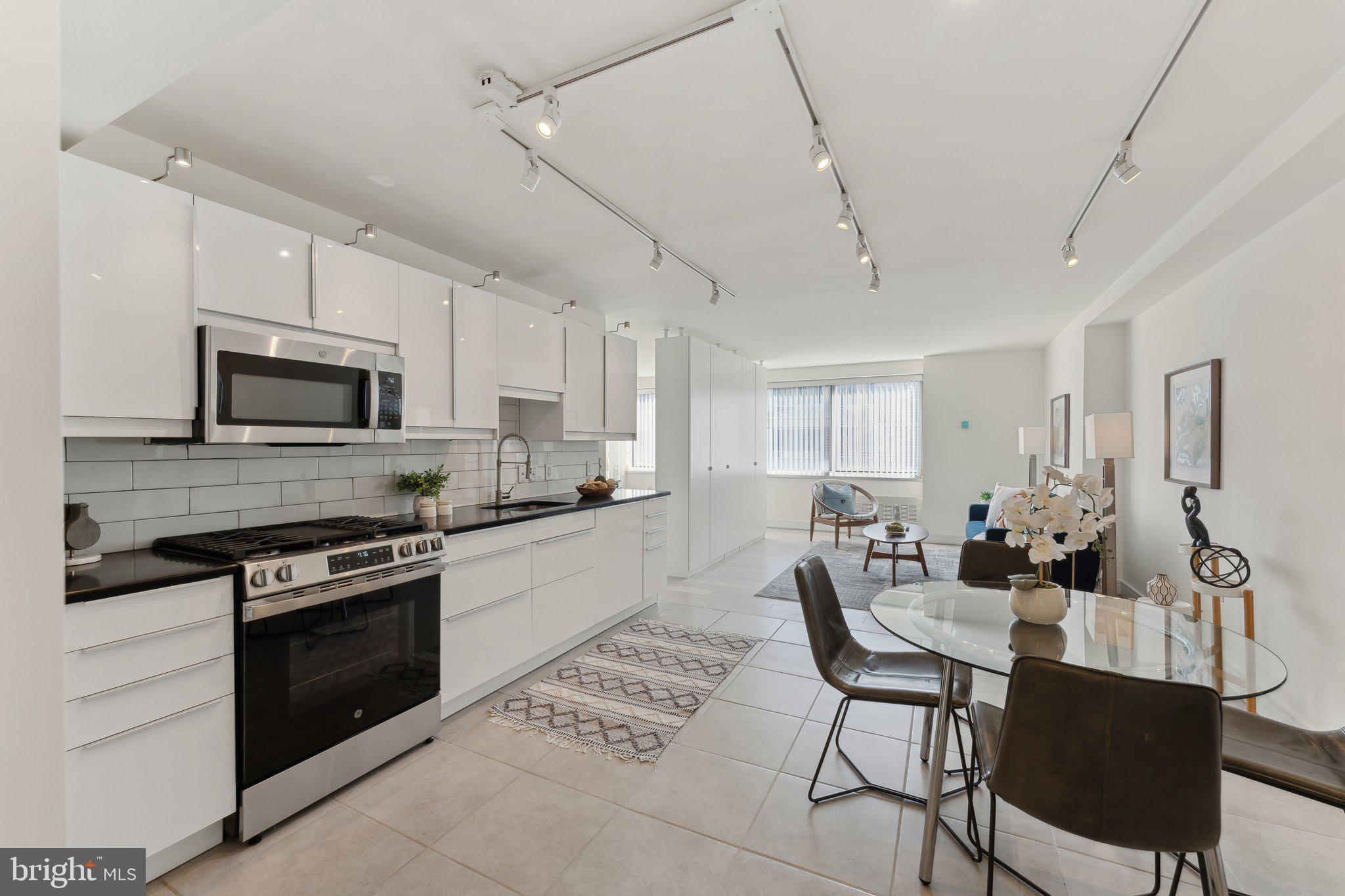 800 4th Street Southwest, Unit S419 Washington, DC 20024 - Photo 16 of 32 a kitchen with stainless steel appliances kitchen island granite countertop a stove a sink dishwasher a dining table and chairs with wooden floor