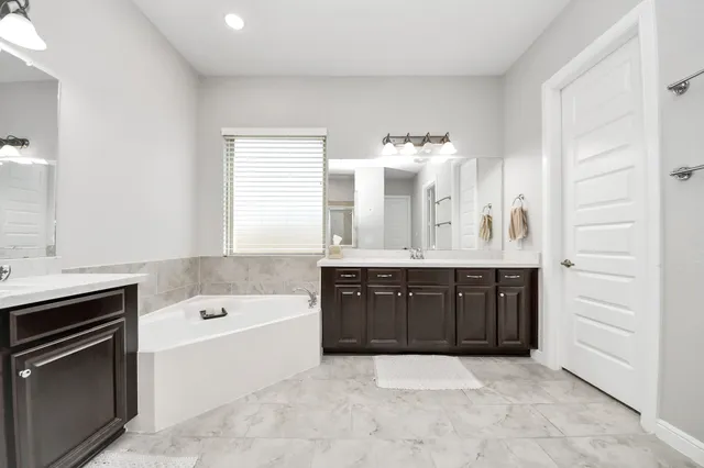 a spacious bathroom with a tub sink and mirror