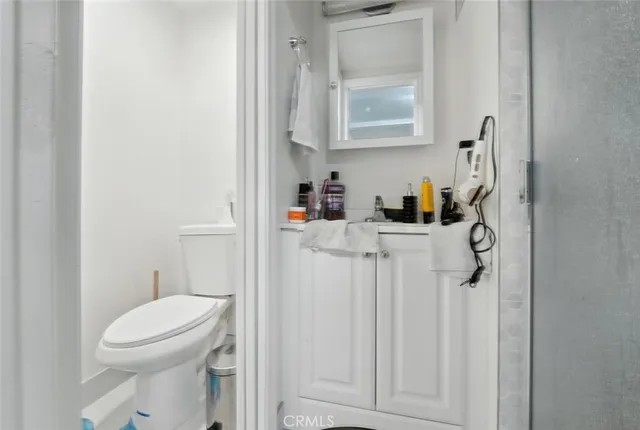 a bathroom with a toilet sink washing machine and mirror