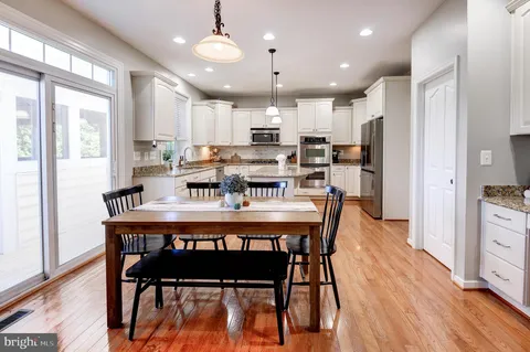 a kitchen with stainless steel appliances granite countertop a stove a sink refrigerator and a dining table with wooden floor