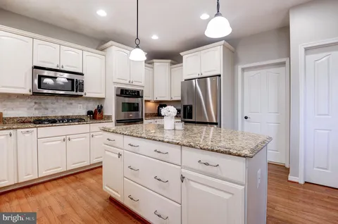 a kitchen with stainless steel appliances granite countertop a stove a sink and a microwave