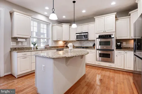 a kitchen with kitchen island granite countertop a stove a sink and a microwave