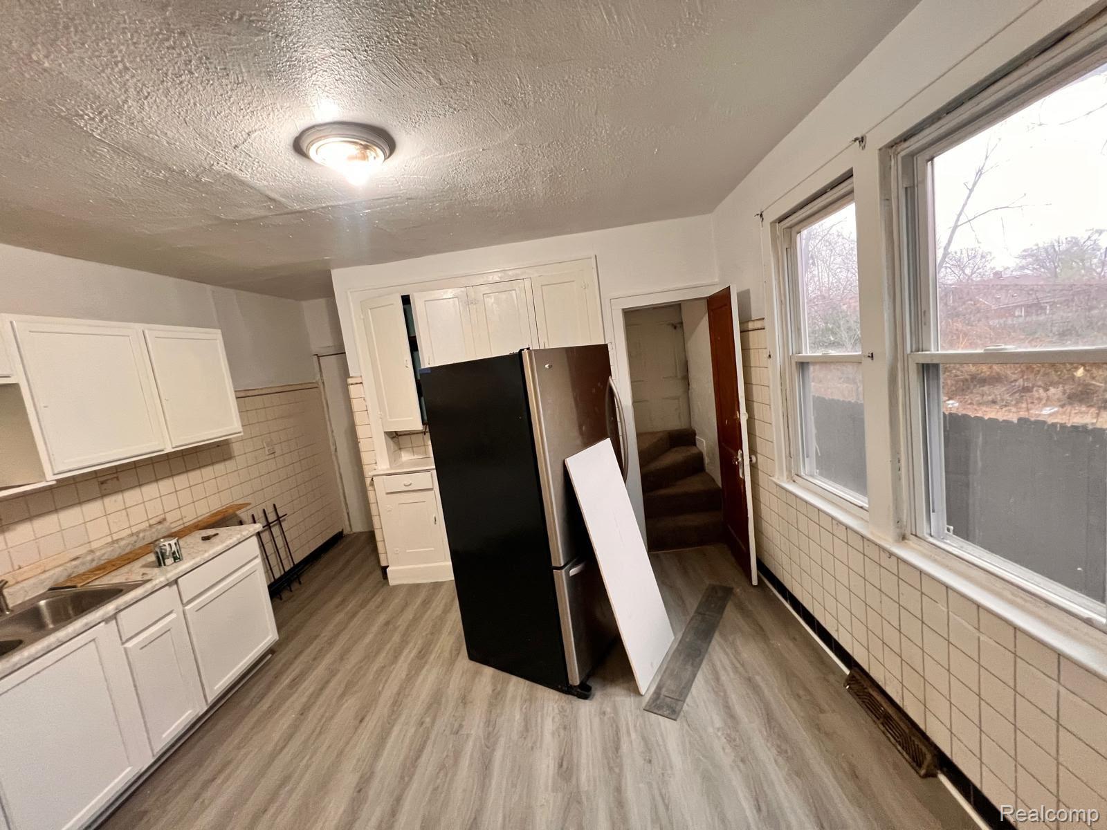 13768 Gable Street Hamtramck, MI 48212 - Photo 3 of 12 Kitchen featuring wood-finish flooring, white cabinetry, and light-colored tile wainscoting