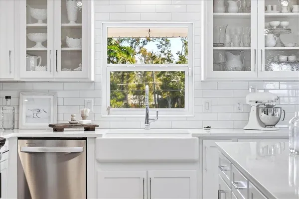 a kitchen with stainless steel appliances kitchen island granite countertop a refrigerator a sink dishwasher a stove and white cabinets with wooden floor