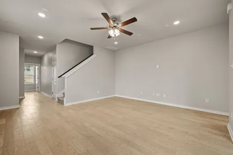 an empty room with ceiling fan and wooden floor