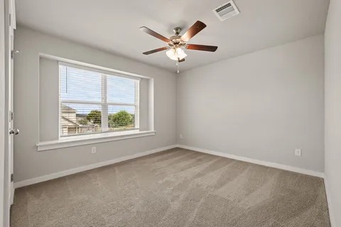an empty room with window and ceiling fan