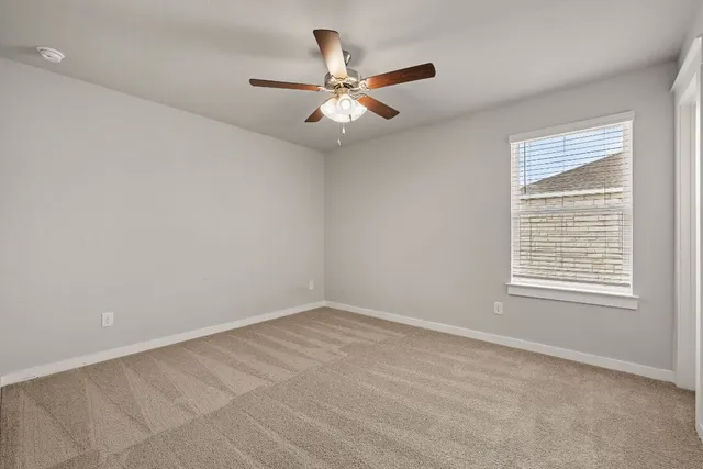 an empty room with a window and a fan