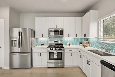 a kitchen with white cabinets and stainless steel appliances