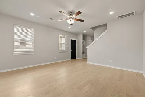 a view of an empty room with a ceiling fan and window