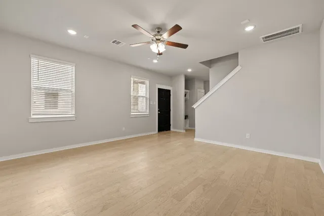 a view of an empty room with a ceiling fan and window
