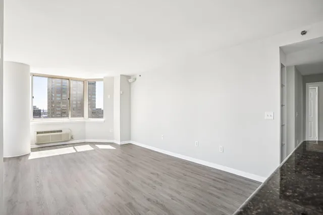 a view of empty room with wooden floor and a window