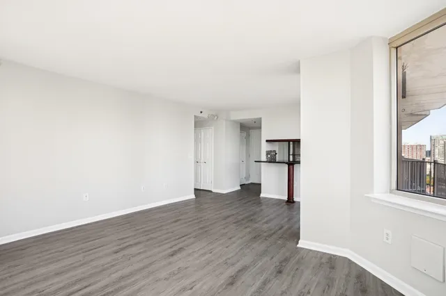 a view of an empty room with a window and wooden floor