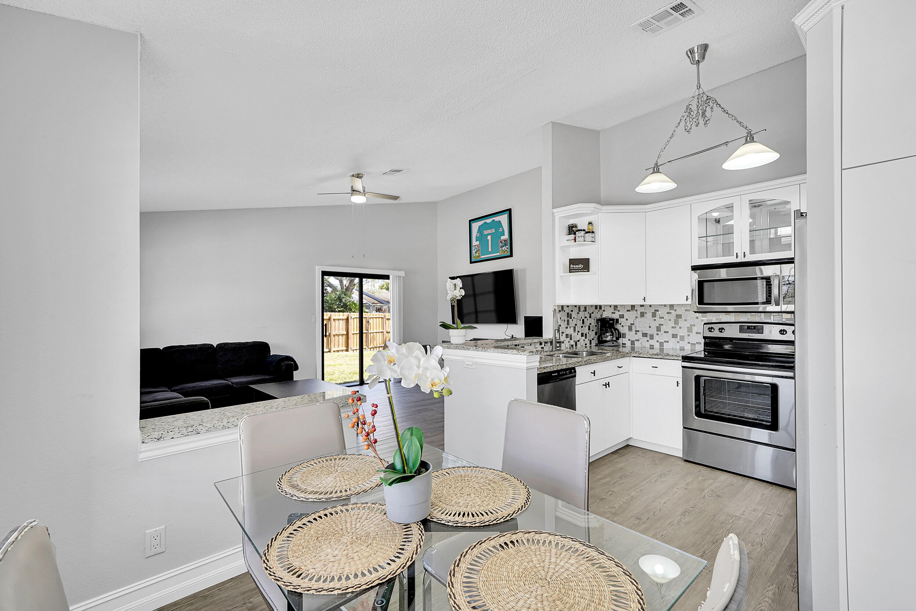 11120 North Terradas Lane Boca Raton, FL 33428 - Photo 11 of 57 a kitchen with stainless steel appliances a stove a sink dishwasher a dining table and chairs with wooden floor