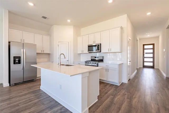 a kitchen with sink a wooden floor and stainless steel appliances