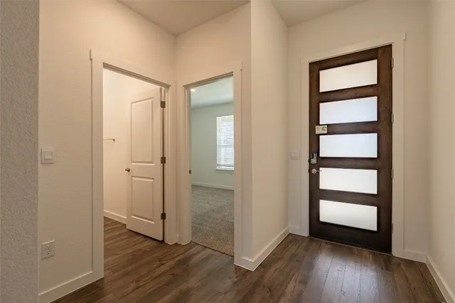 an empty room with wooden floor closet and windows