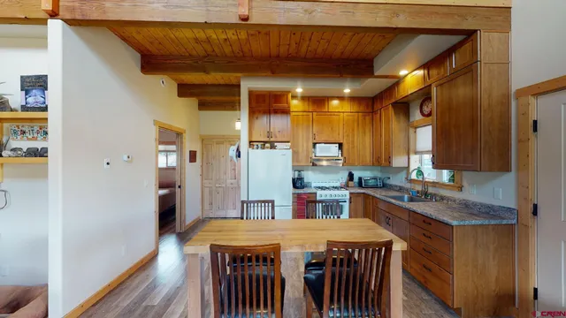 a kitchen with stainless steel appliances granite countertop a table chairs and a refrigerator