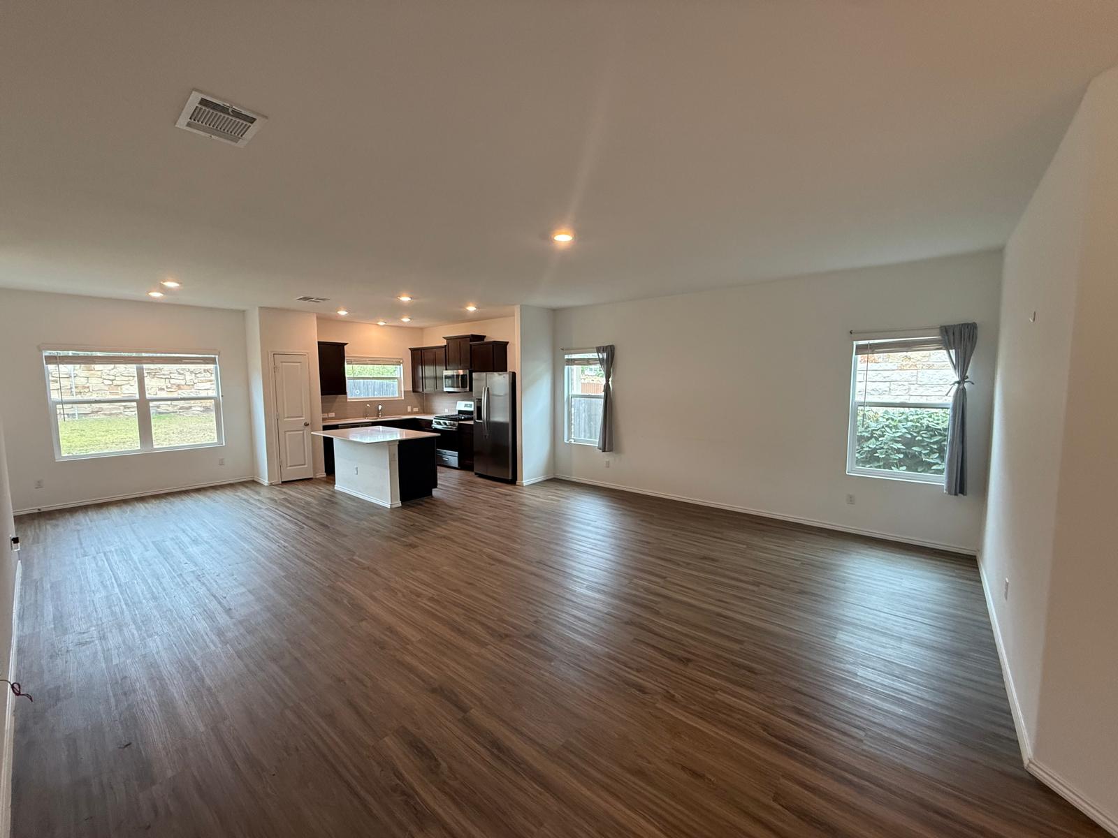 1521 Brueggerhoff Road Leander, TX 78641 - Photo 4 of 15 Rich wood floors sweep through this expansive, open-concept living space adjacent to the kitchen.