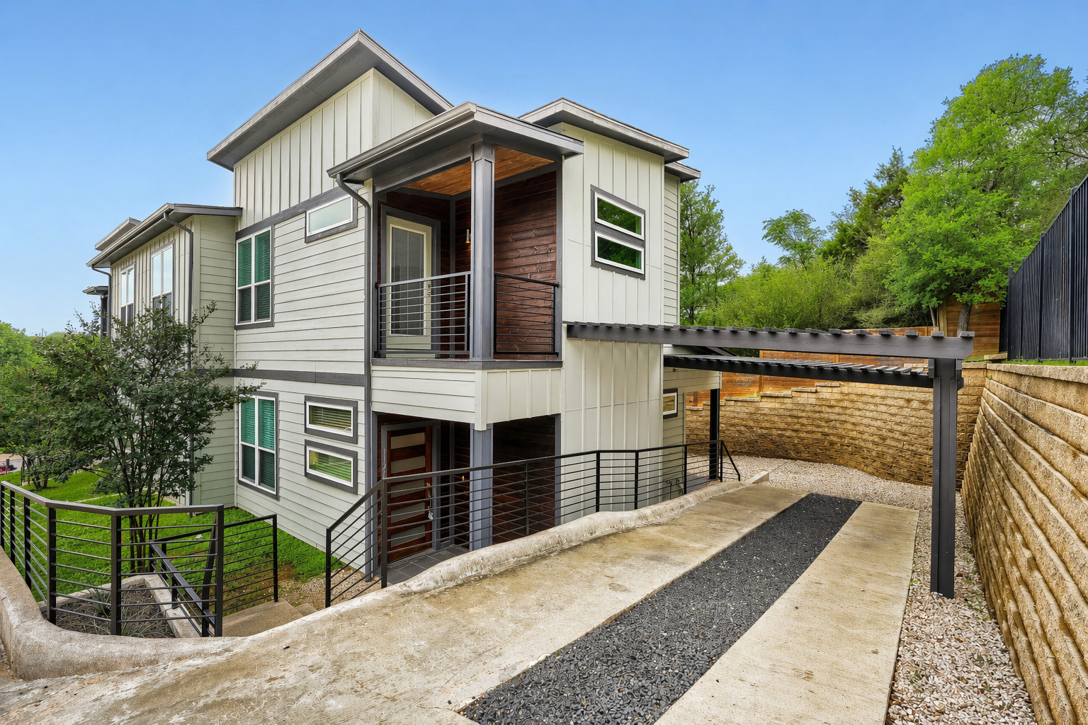 Contemporary three-story residence featuring light gray siding and dark trim accents
