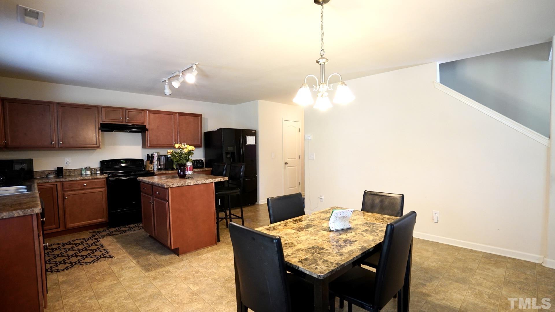 6813 Planting Court Raleigh, NC 27610 - Photo 4 of 9 a kitchen with granite countertop kitchen island stainless steel appliances a refrigerator a stove a sink a dining table and chairs