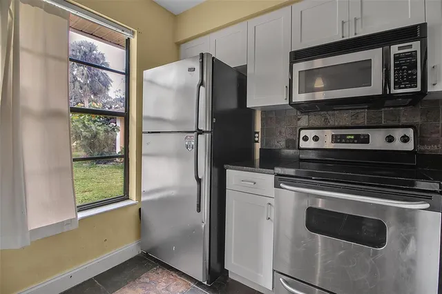 a kitchen with granite countertop a refrigerator stove and microwave