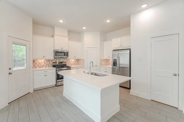 a kitchen with a sink a stove a refrigerator and white cabinets