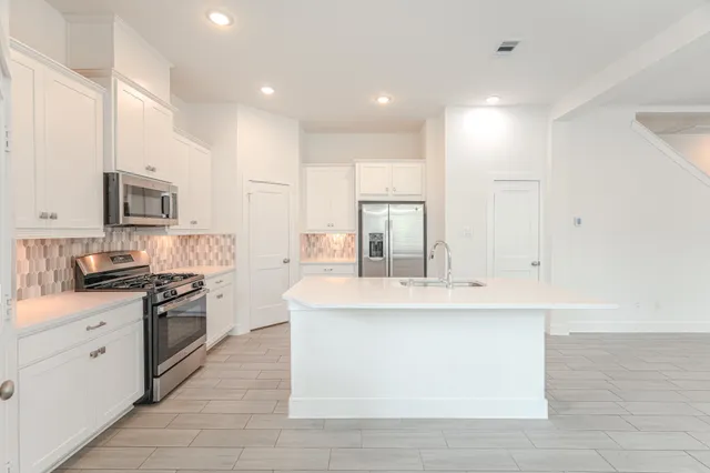 a large kitchen with stainless steel appliances granite countertop a stove a sink and a refrigerator