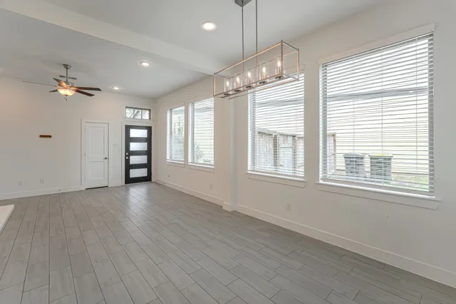 a view of an empty room with a window and wooden floor