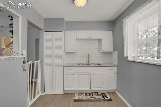 a kitchen with white cabinets and window