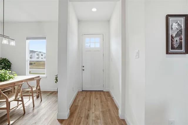a view of a hallway and wooden floor a livingroom with windows
