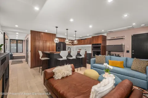 a living room with furniture kitchen view and a chandelier