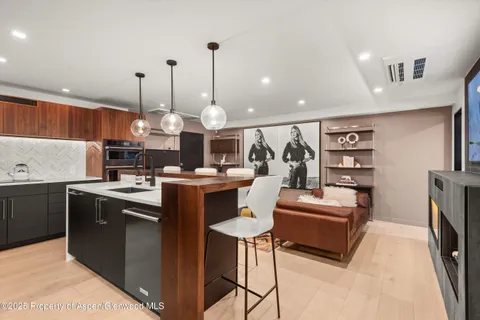 a kitchen with stainless steel appliances kitchen island granite countertop a sink a stove and a wooden floors