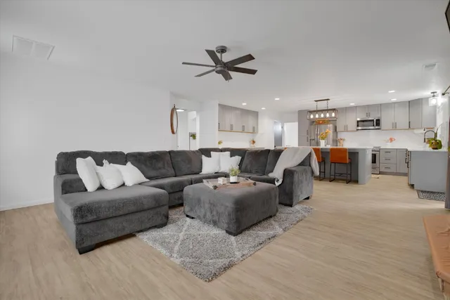 a living room with furniture kitchen view and a chandelier
