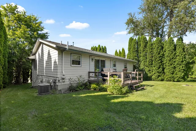 a view of backyard with table and chairs and potted plants and large trees