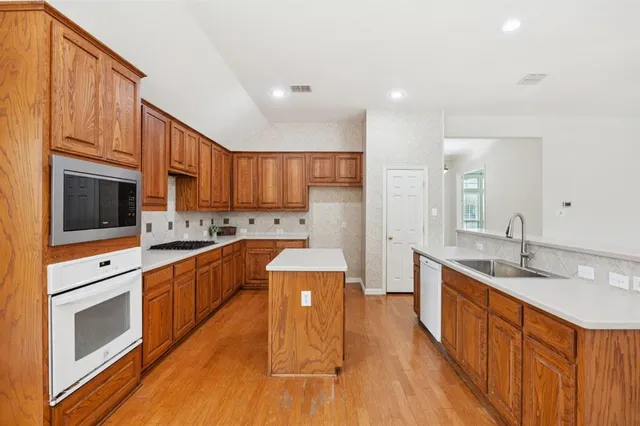a large kitchen with stainless steel appliances granite countertop a stove a sink and a refrigerator