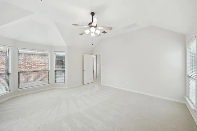 an empty room with chandelier fan and windows