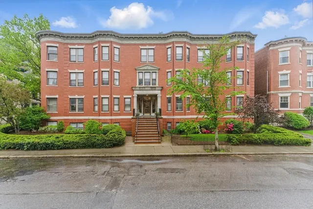 a front view of a brick building next to a yard