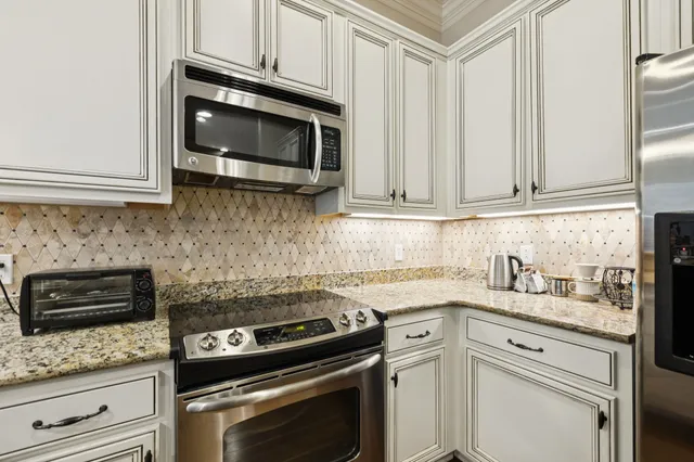 a kitchen with granite countertop white cabinets and stainless steel appliances