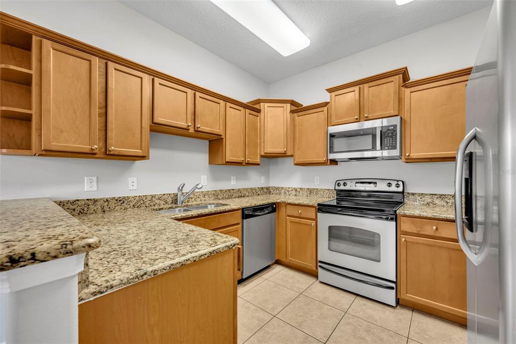 3201 Sonesta Court, Unit A Clermont, FL 34711 - Photo 10 of 34 a kitchen with stainless steel appliances granite countertop a stove sink microwave and cabinets