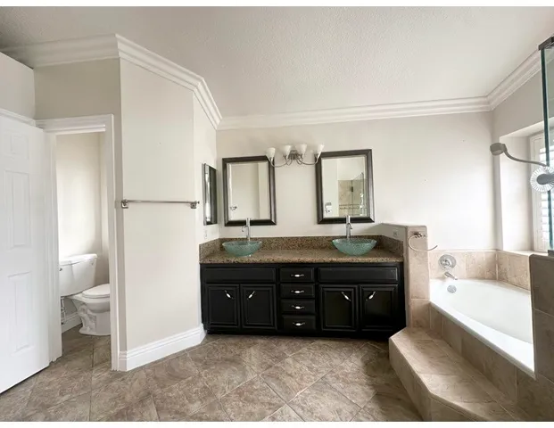a spacious bathroom with a granite countertop sink a toilet and a bathtub